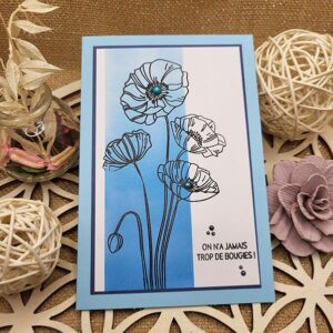 Carte d’anniversaire artisanale bleue avec coquelicots noirs, message humoristique "On n’a jamais trop de bougies !" et enveloppe assortie.
